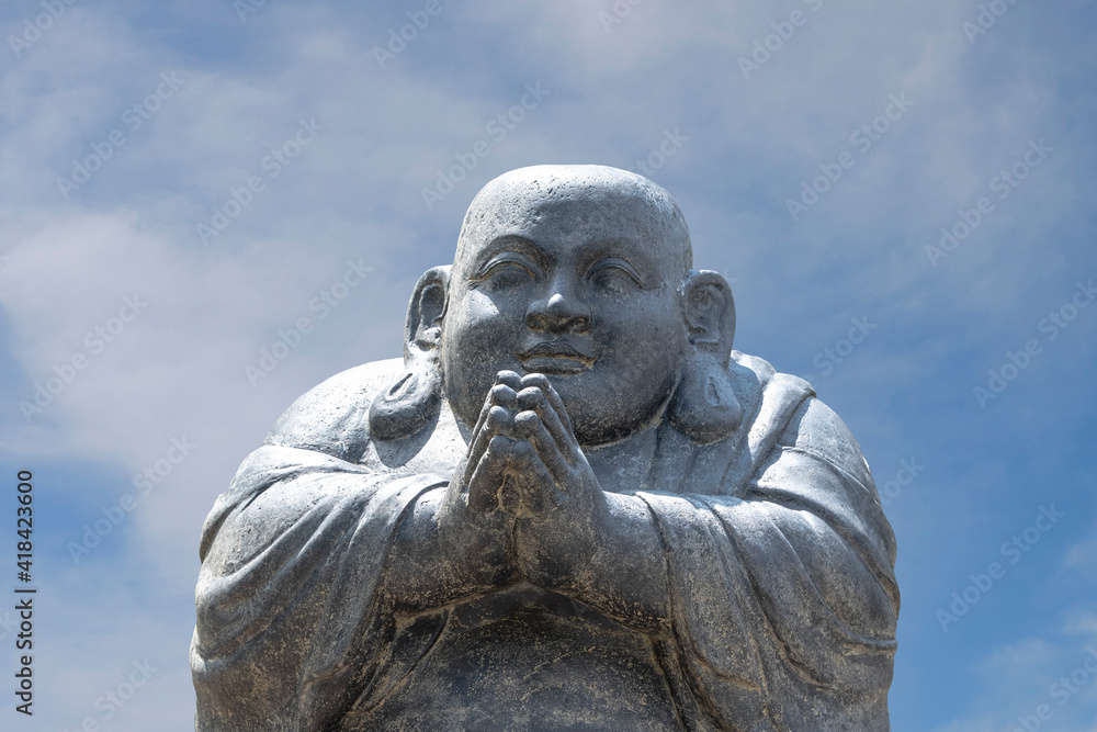 Happy Buddha figure, at sunset before the blue sky