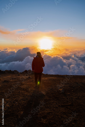 Climber on top of Acatenango volcano in Guatemala watching the sunset - woman hiking on top of the volcano at sunset