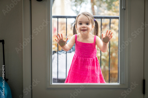Girl with face pressed to glass door looking into house