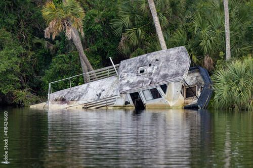 Distroyed Flat bottom barge style boat rests on its side, damaged by hurricane