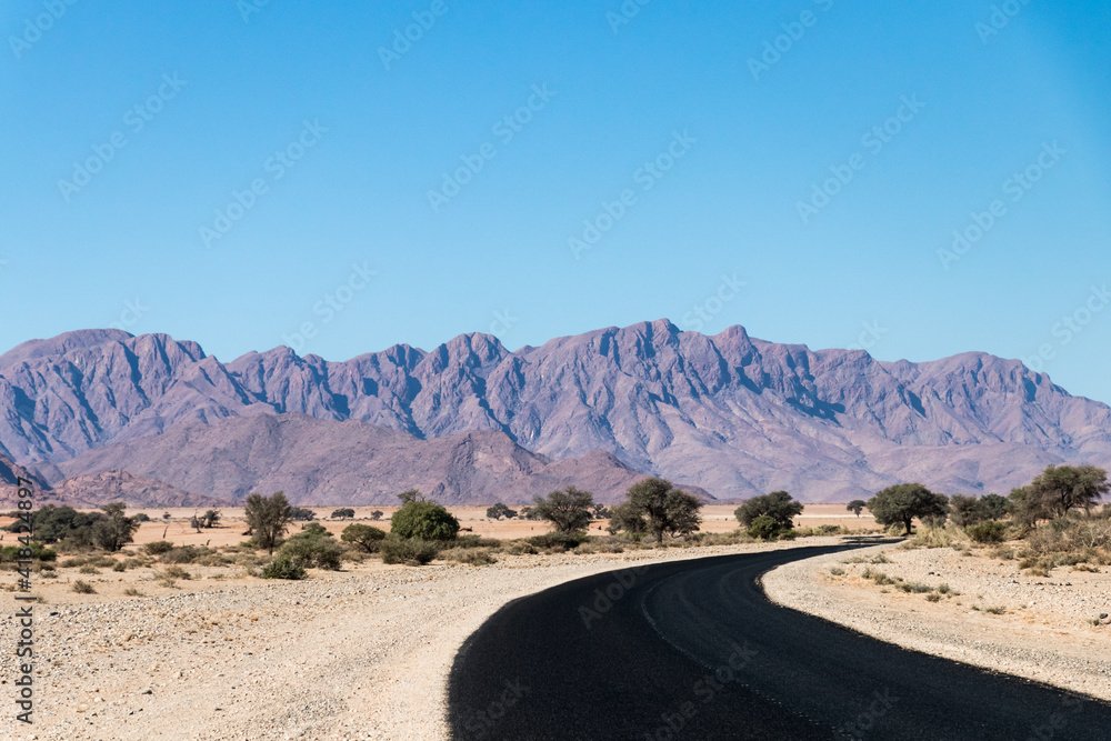 view along a brand new black asphalt road onto the Naukluft mountains close to Sesriem, Namibia- road trip