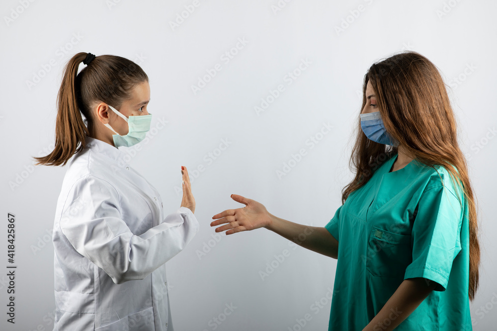 Nurse in green uniform giving handshake to a female doctor in white uniform Nurse in green uniform giving handshake to a female doctor in white uniform