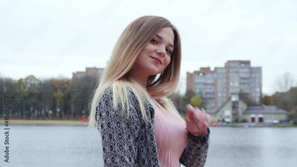 Girl posing in the autumn evening against the backdrop of a city lake.