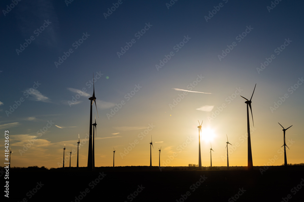 viele Windräder bei Sonnenuntergang stehen auf einem Feld und produzieren Strom viele Windräder bei Sonnenuntergang stehen auf einem Feld und produzieren Strom