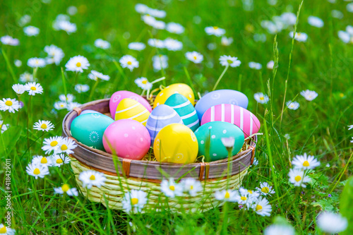 viele bunte Ostereier in einem Korb auf der Wiese	