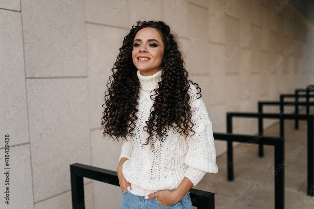 Fototapeta premium In the light tunnel stands curly brunette with a charming smile. High quality photo