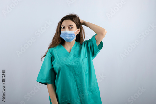 Young beautiful nurse in green uniform wearing a medical mask
