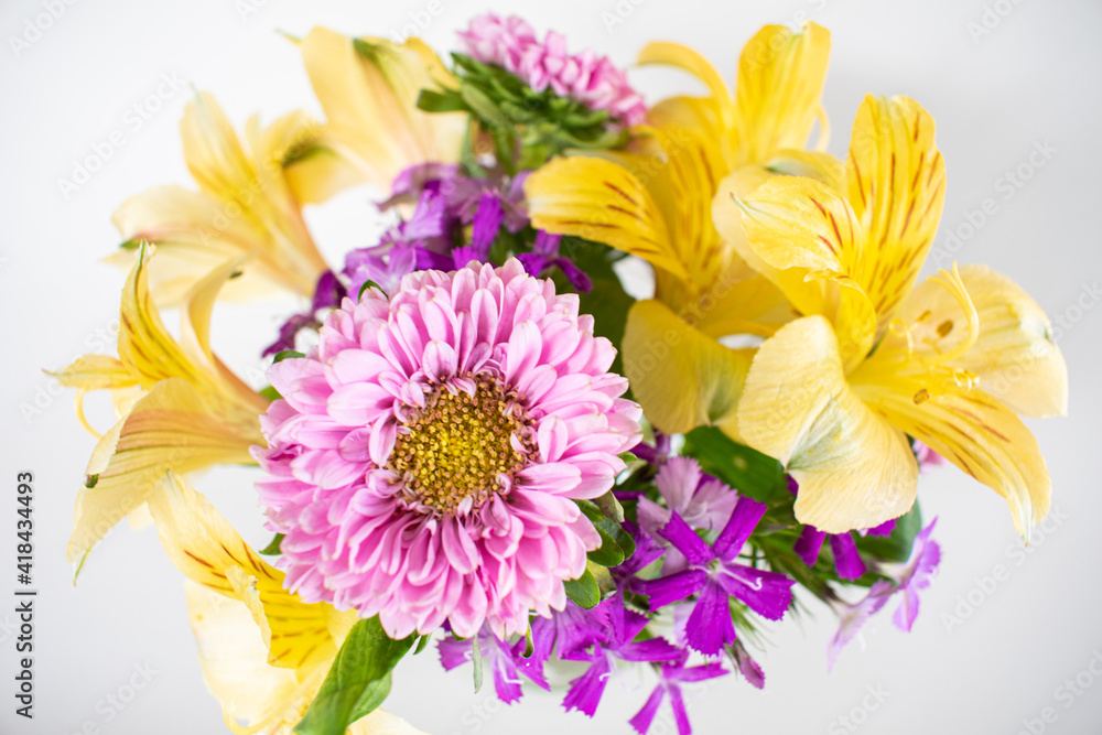 Small pink and yellow flower arrangement of asters and alstromeria in a vase. Colorful spring flower arrangement isolated on white.