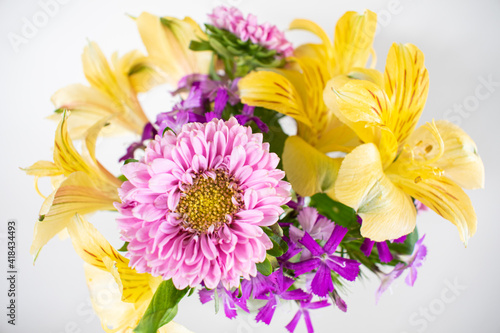 Small pink and yellow flower arrangement of asters and alstromeria in a vase. Colorful spring flower arrangement isolated on white.