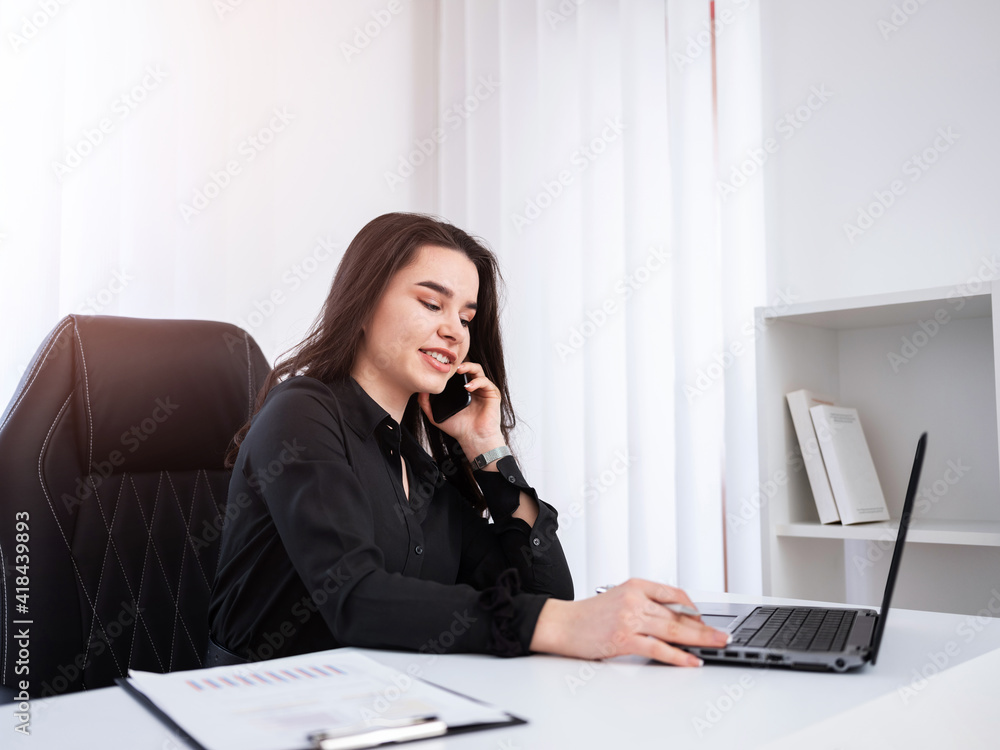 Young business owner talking on the phone in her office. Young business owner talking on the phone in her office.