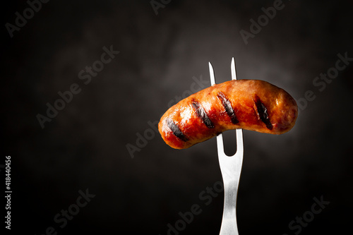Grilled barbecue sausages on dark background.