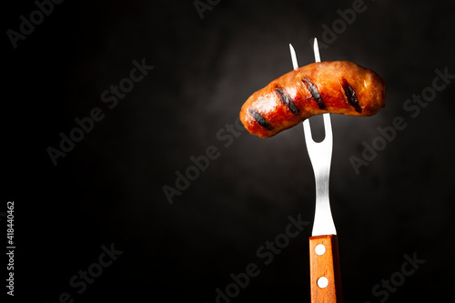 Grilled barbecue sausages on dark background.
