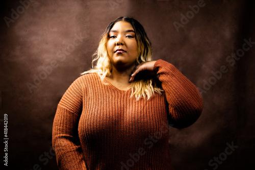 Black girl flips hair wearing orange sweater, 