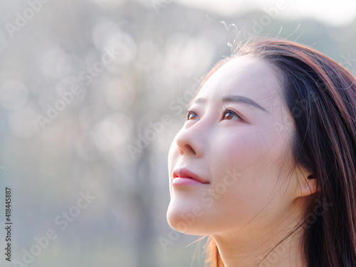 Close up portrait of beautiful young Chinese woman  looking away with smiling expression  head shot side view with left copy space.