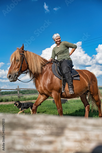 Young beautiful girl rides a horse in the paddock. © shymar27