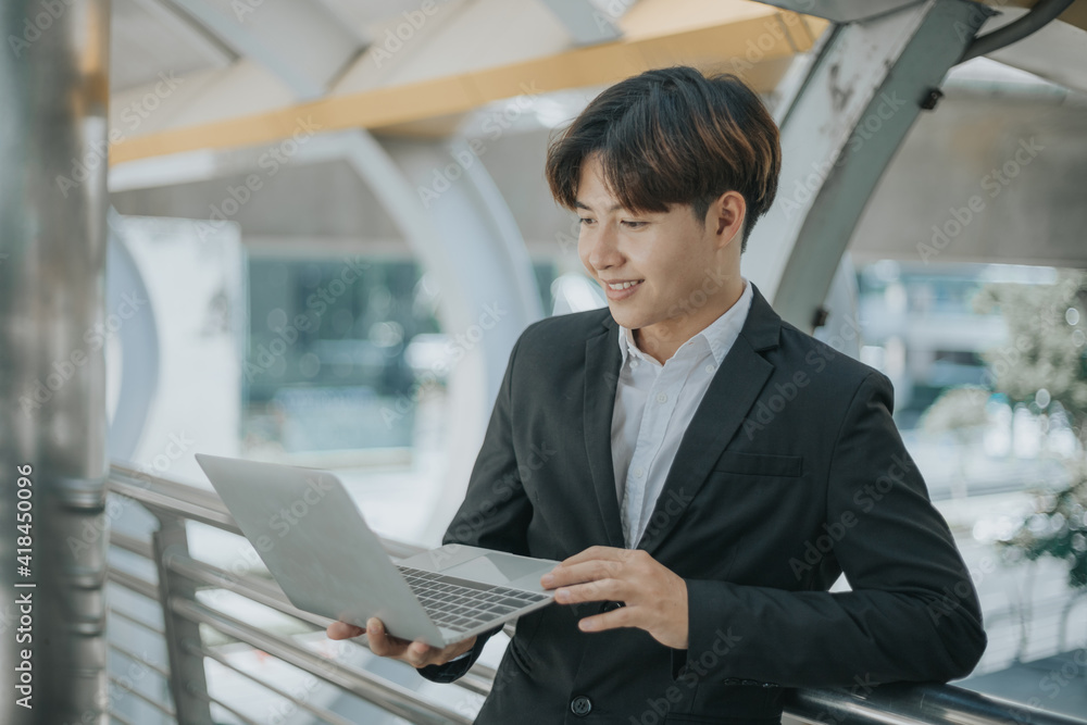 Fototapeta premium Asian businessman using laptop outdoor.