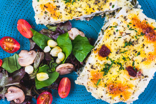 Vegetarian lasagne topped with toasted pine nuts and melting cheeses. Salad photo