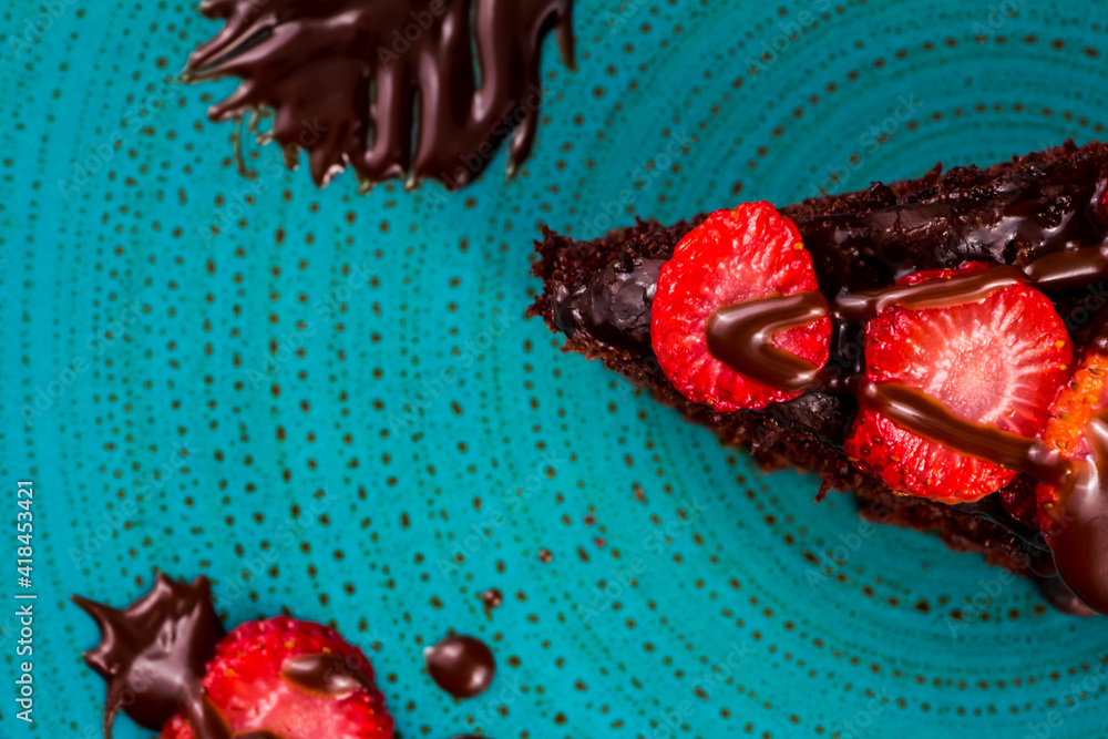 Naklejka premium chocolate cake with strawberries in turquoise dish