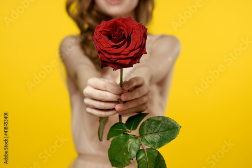 Beautiful woman in a rose flower dress in the hands of a charm gift yellow background © SHOTPRIME STUDIO