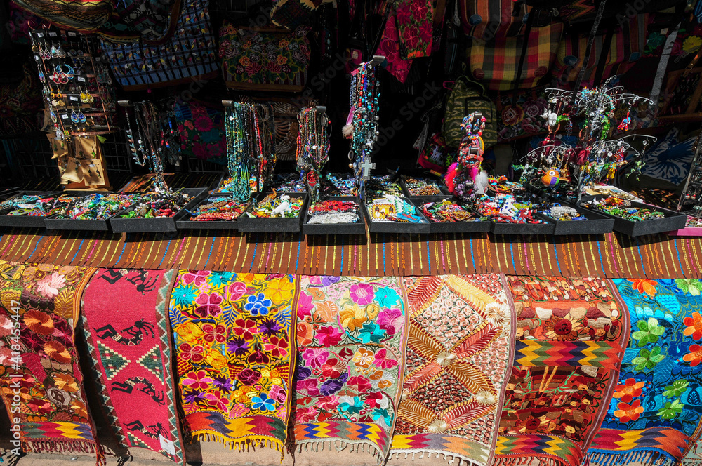 Colorful table runners, jewelry and purses on display at market stand 