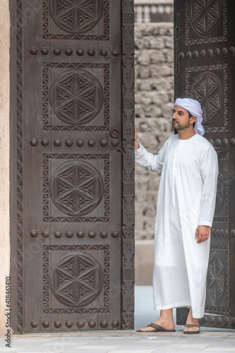 arab man in traditional clothing coming out of a door