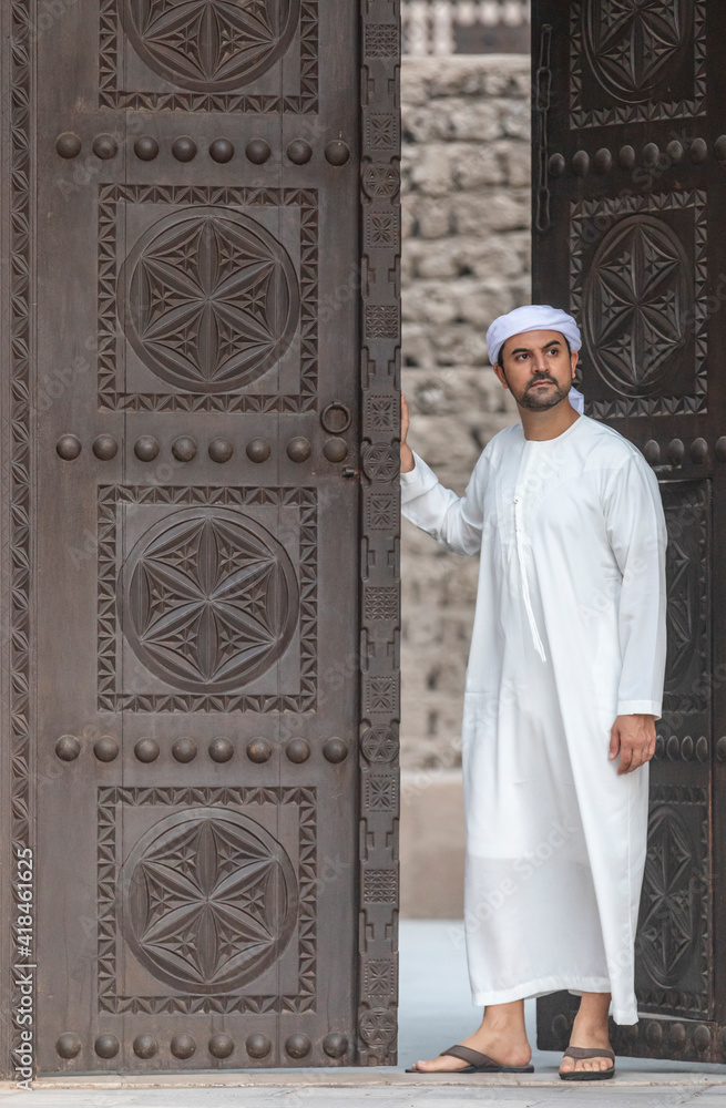 arab man in traditional clothing coming out of a door