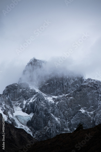 The peak of a mountainf with snow and fog, in a cloudy day