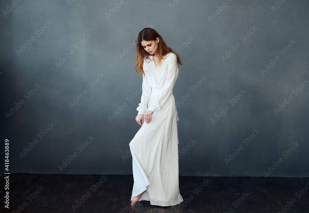 Portrait of an attractive woman in a white dress on a gray background in full growth Portrait of an attractive woman in a white dress on a gray background in full growth