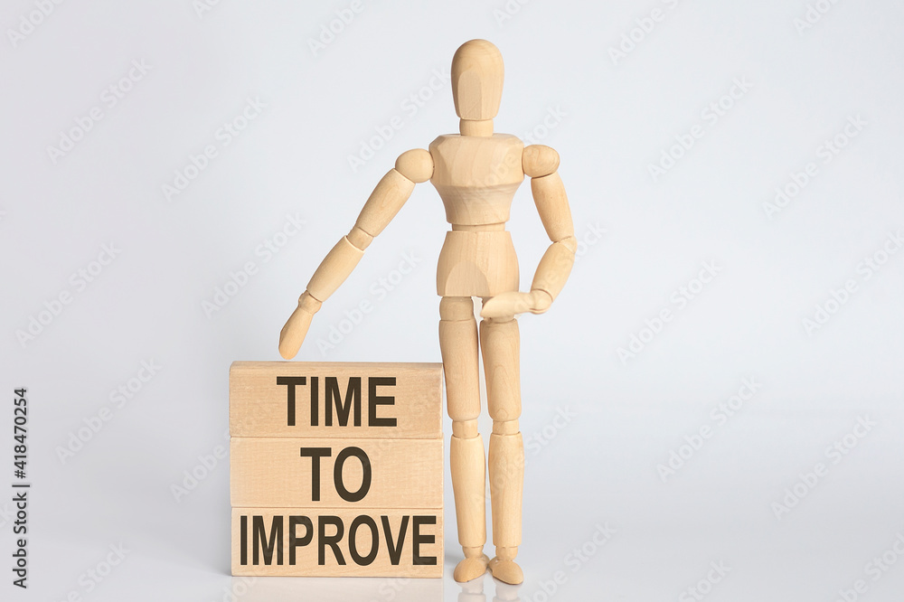 Wooden man shows with a hand text TIME TO IMPROVE concept on the wooden block Wooden man shows with a hand text TIME TO IMPROVE concept on the wooden block