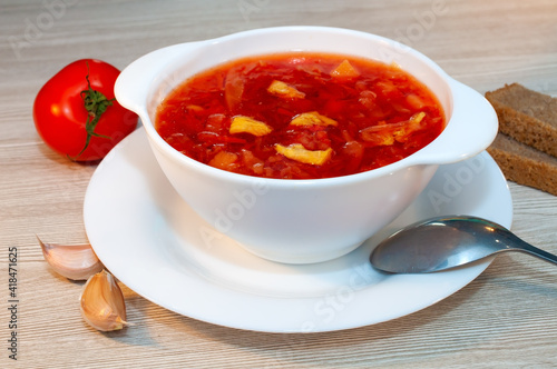 Borscht soup with meat in a white bowl on a wooden table