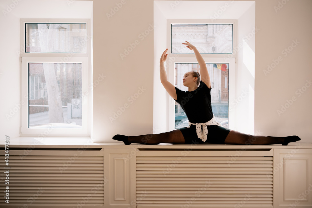 Teenager girl doing string near the window while practicing stretching at home Teenager girl doing string near the window while practicing stretching at home