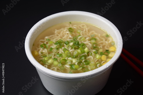 Noodles in plastic bowl, traditional asian meal on dark background, junk food concept