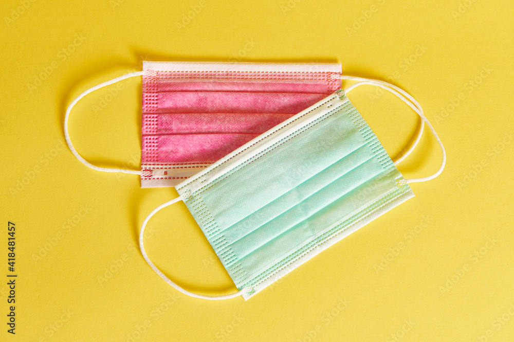 Multicolored medical protective masks on yellow background with copy space. Flat lay Multicolored medical protective masks on yellow background with copy space. Flat lay