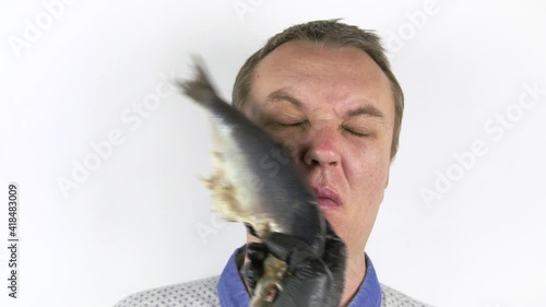 Fresh herring hits a young man's face. Funny man gets slapped in the face with wet fresh fish.the concept of a quarrel, a video blogger Challenge