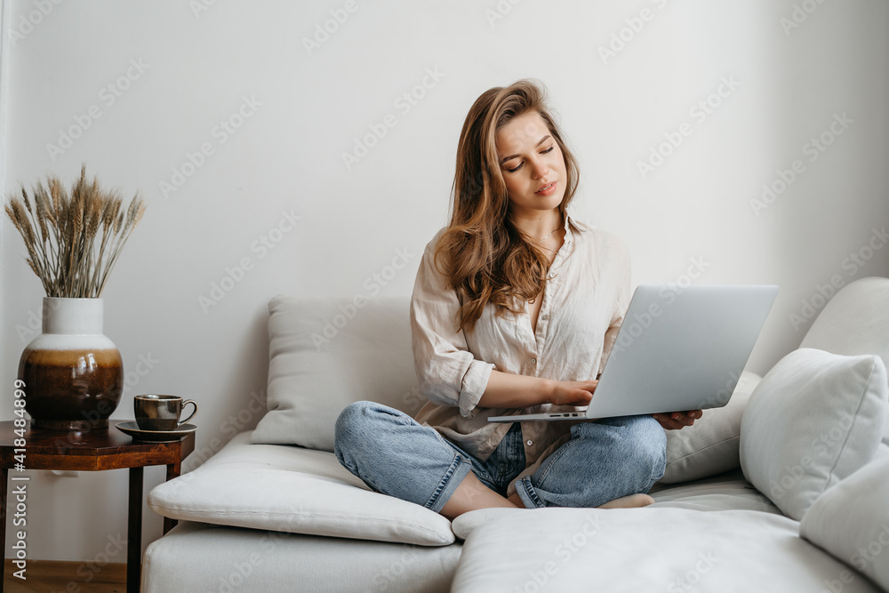 Portrait of a young female freelancer sitting on the couch and working on project, watching movie on laptop, studying, blogging, resting and chatting online Portrait of a young female freelancer sitting on the couch and working on project, watching movie on laptop, studying, blogging, resting and chatting online