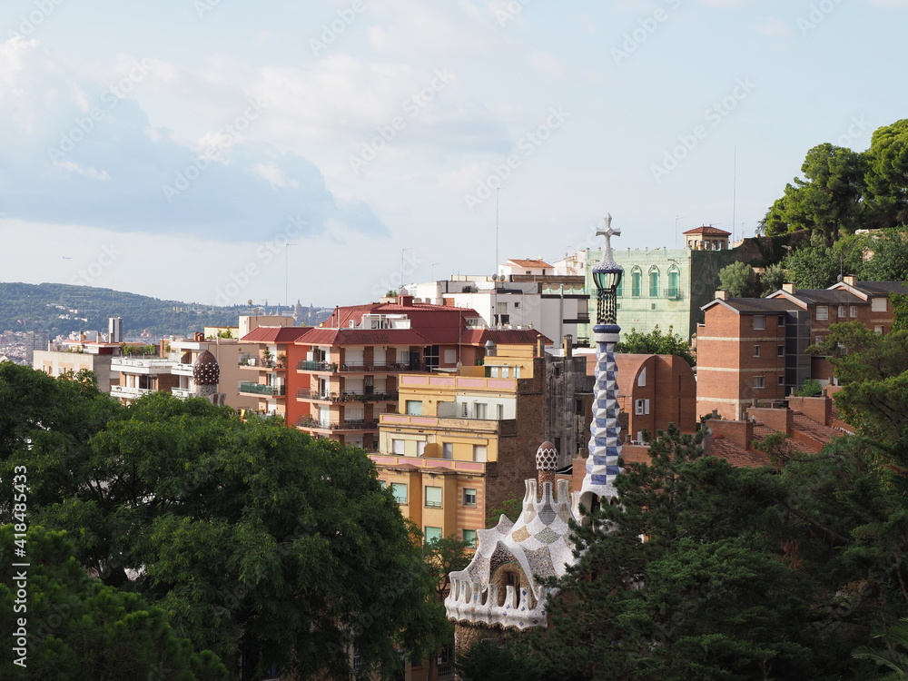 Colored townscape of european city of Barcelona at Catalonia district in Spain and chimney of entrance building to Park Guell, cloudy blue sky in 2019 warm sunny summer day on September.
