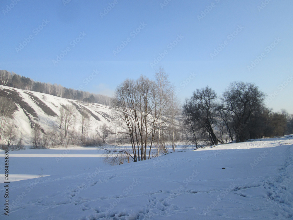 Fototapeta premium frozen riverbed in winter in the snow with a cliff on the bank of the hill nature in Siberia