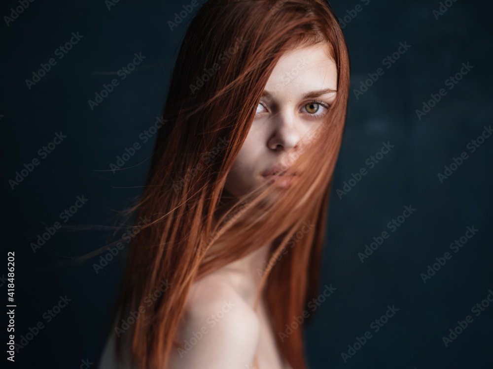 Close-up cropped view of a woman with red hair looking forward on a black background Close-up cropped view of a woman with red hair looking forward on a black background