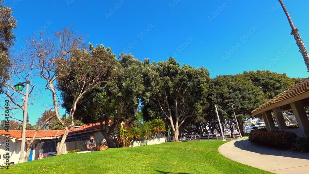 Aerial moving forward through trees and exploring a green city park under a bright clear blue sky, with walkways, grass, and park buildings - Los Angeles, California Aerial moving forward through trees and exploring a green city park under a bright clear blue sky, with walkways, grass, and park buildings - Los Angeles, California