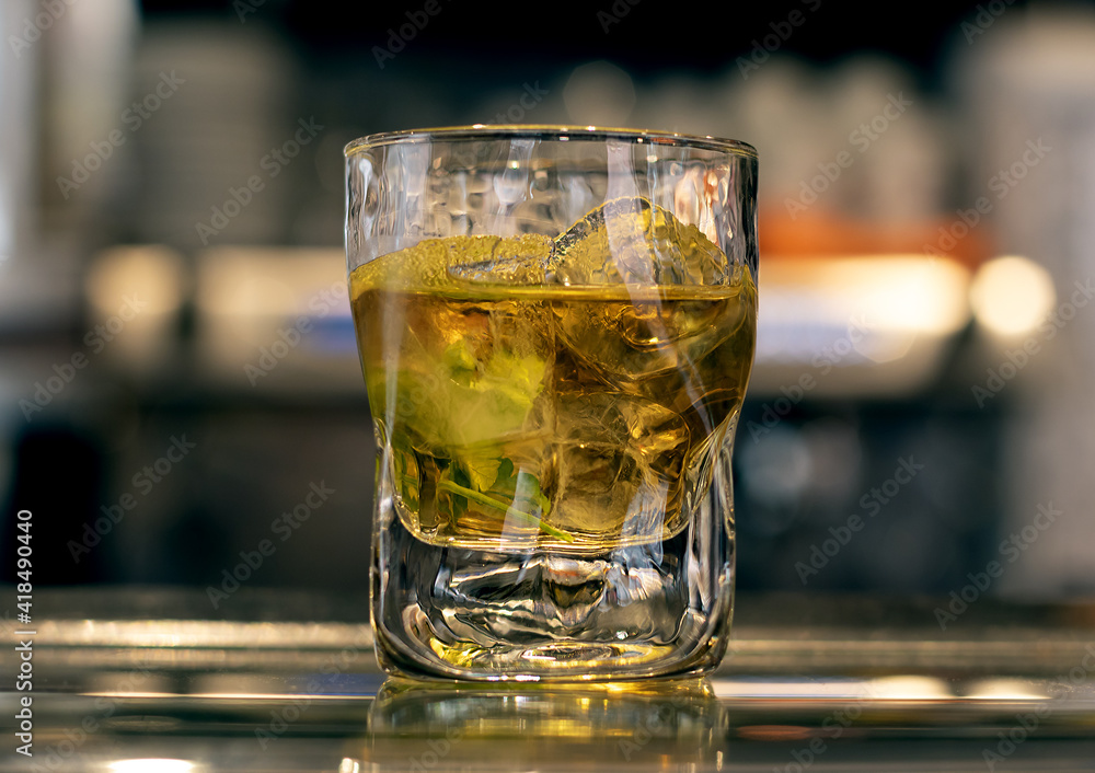 Rum or mojito drink in a glass with ices on a bar counter