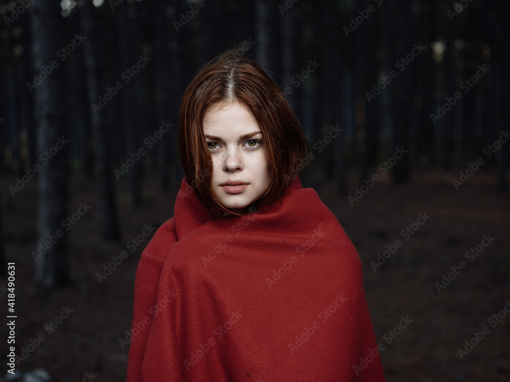 A frozen woman with a red blanket on her shoulders in the forest A frozen woman with a red blanket on her shoulders in the forest