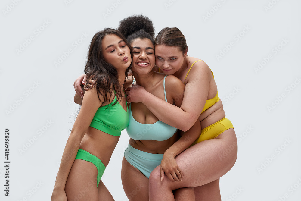 Three joyful young women with different body types in colorful underwear  having fun while posing together isolated over white background Stock Photo