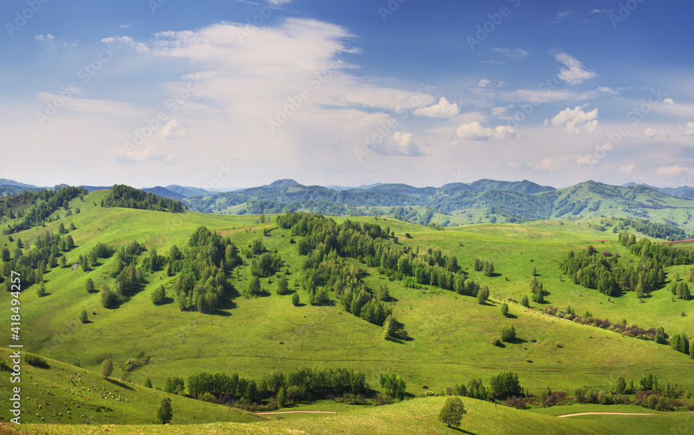View of green hills and blue sky with clouds, countryside