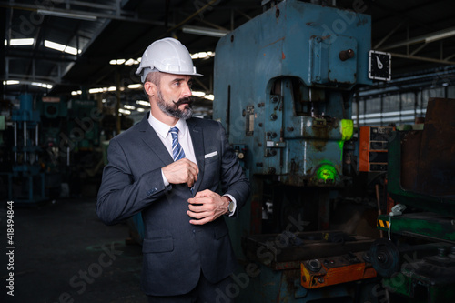 Portrait of confident business people wearing hardhats in metal factory