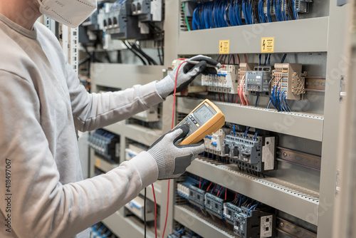 Electricians hands testing current electric in control panel