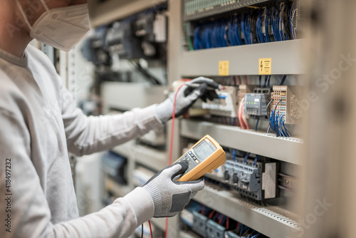 Electricians hands testing current electric in control panel
