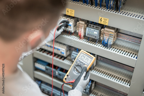 Electricians hands testing current electric in control panel