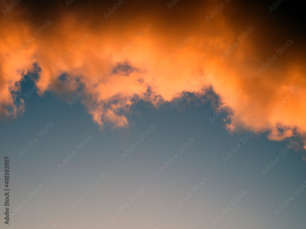 Dark blue sky with heavy clouds. The clouds have golden and brown hues. Tragic atmosphere. Natural background with copy space.