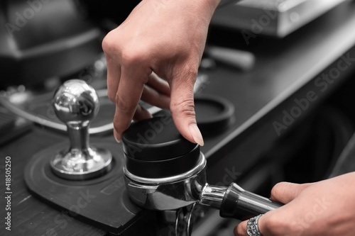 Obraz na płótnie Closed up of barista’s hand tamping the portafilter before making fresh coffee in a coffee shop