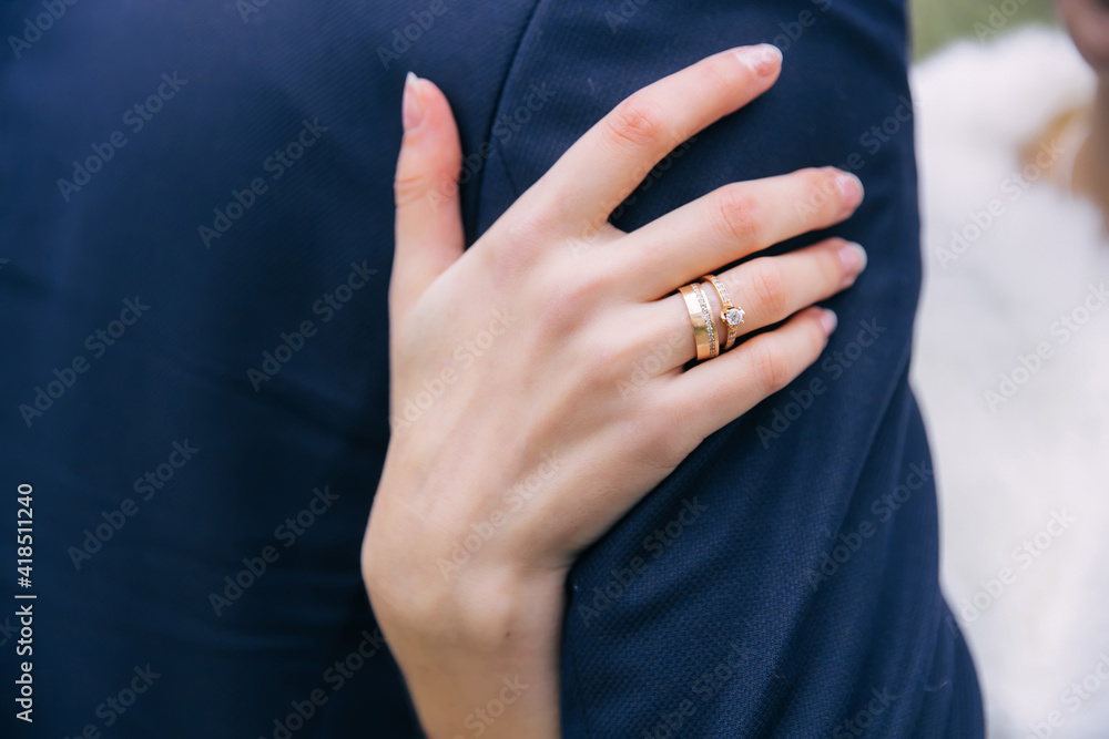 the bride's hand in wedding rings hugs the groom's shoulders.wedding concept. the bride's hand in wedding rings hugs the groom's shoulders.wedding concept.